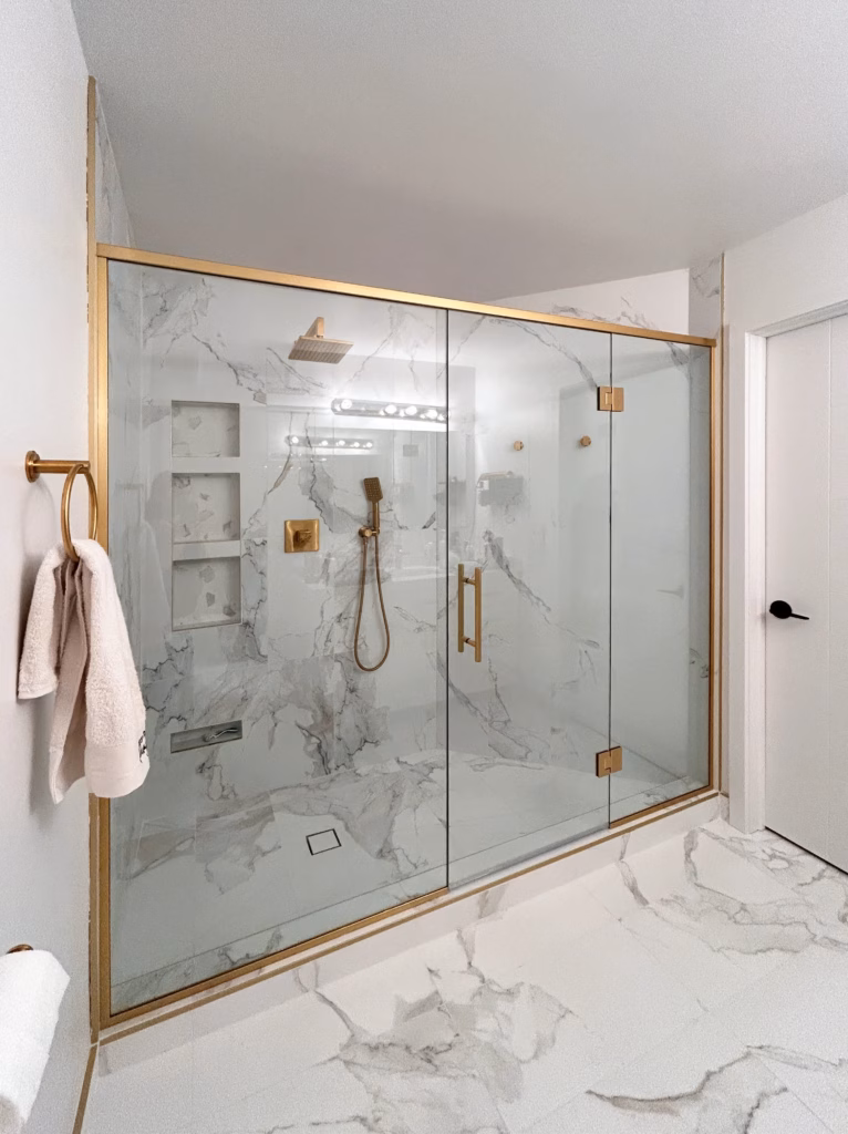Wide-angle view of a shower with gold fixtures and natural stone tile