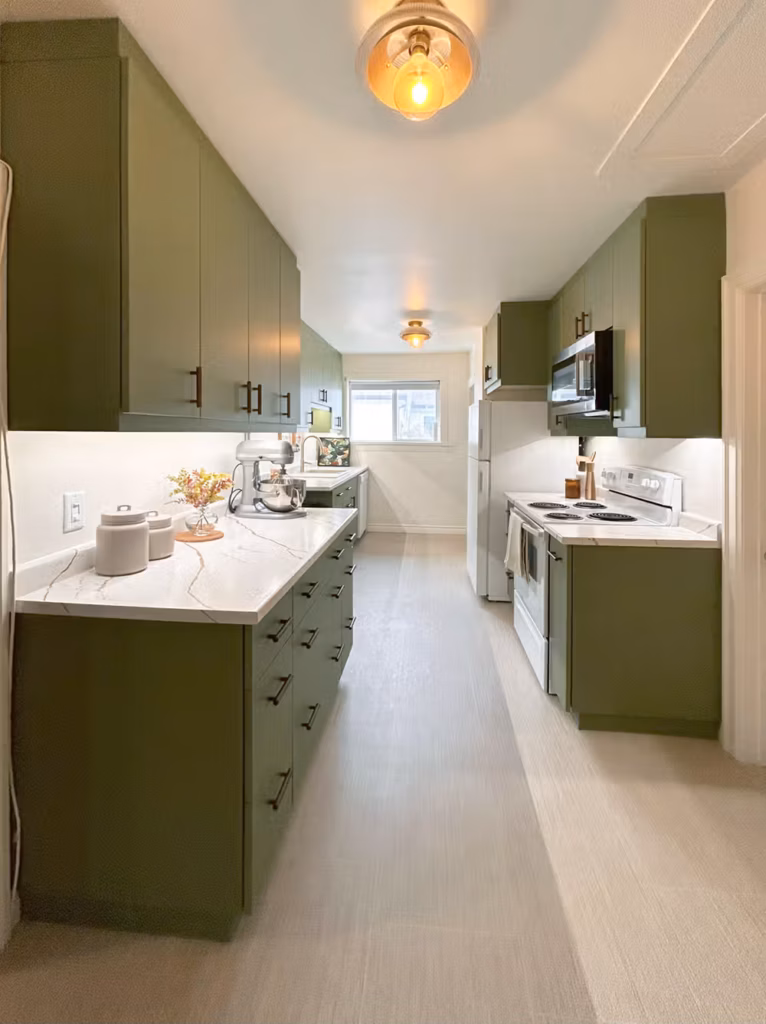Full-length view of the renovated Ferry Road galley kitchen with olive green cabinets on both sides and white appliances