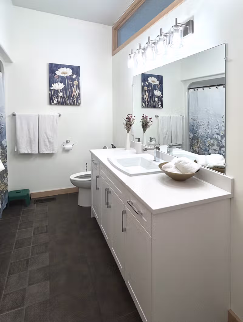Loudoun Avenue bathroom after renovation, featuring a new white double-sink vanity with quartz countertop and matching mirror