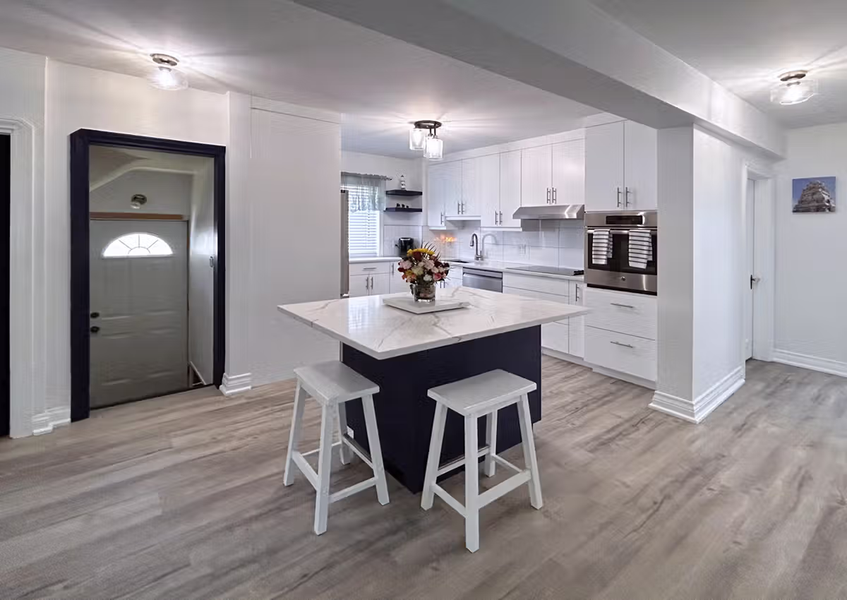 Machray Avenue home after renovation, featuring an open white kitchen with a navy blue island opening to the entryway