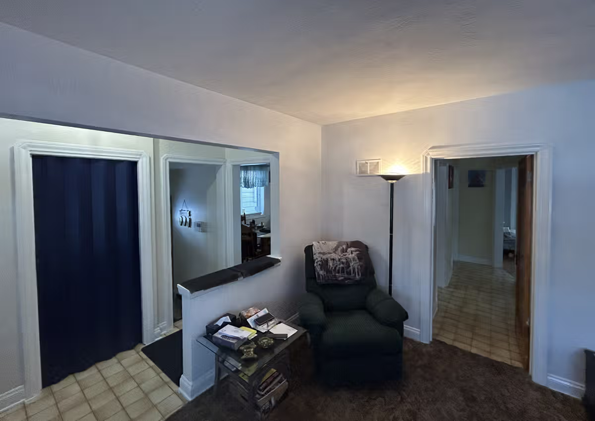 Machray Avenue home before renovation, showing the original living room with dated flooring and dark paneled walls