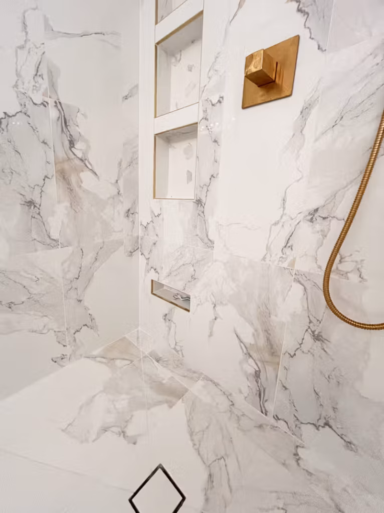 Marble shower with built-in niche shelves and brushed gold fixtures